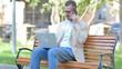 © stockbakers - Middle Aged Man Talking on Phone and Using Laptop Outdoor