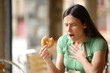 © Antonioguillem - Woman choking eating doughnut in a bar