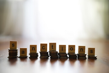 Poster - Word Sanctions made of wooden block letters with coins stacks