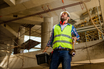 Wall Mural - A portrait of a foreman in his 40s who descends the stairs with a tool box on the construction site.