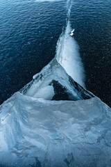 Natural blue ice on the lake. Beautiful winter landscape. Cracks in the ice. Frozen lake surface.