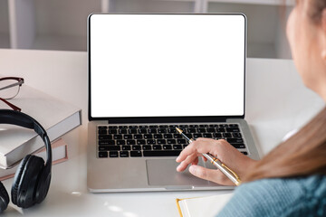 Asian girl watch studying online using applications, app, e learning distance training course at home. Over shoulder view on mockup image on laptop computer with white screen.