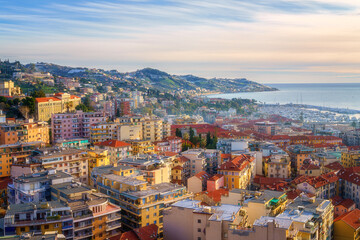 Wall Mural - Panoramic view of Sanremo or San Remo from Pigna hill, Italian Riviera, Liguria, Italy. Scenic sunset landscape with city architecture, sea, green hills, blue water and sky, outdoor travel background