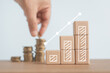 © Ratana21 - increasing graph bar on wooden cube block with blurred hand putting coins to stacking for money saving profit and business investment growth concept