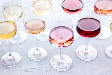 Wall Mural - Wine glasses at a tasting. Rose, red, and white wine, drinks on a table at a winery. An assortment of wines of many different colors and hues