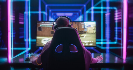 Wall Mural - Young Female Professional Gamer Competing in an E-Sports Championship Event in a Futuristic Neon Arena. Streamer Girl Playing Video Games Online During Cyber Gaming Tournament. Back View Footage