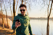 © baranq - Happy man in park using phone during outdoors running exercises