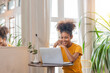 © Natee Meepian - Woman african american smile sitting on desk using laptop. Relax african american lady enjoy her weekend, surfing on internet on laptop at home
