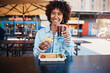 © Flamingo Images - Smiling woman enjoying a drink with some tacos on a restaurant patio