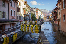 A Picturesque View Of A Narrow Canal In Annecy In Autumn. Quaint Cafes, Bridges, Abundant Flowers, Historic Houses In The Medieval Heart Of Tourist Destination, France