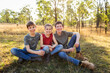 © Austockphoto - Portrait of three happy siblings together in country paddock two boys one girl on farm