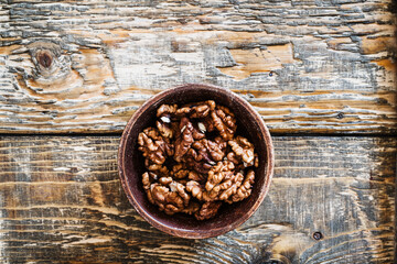 Wall Mural - Bowl of organic walnuts on wooden table, autumn harvest time