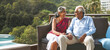 © Reubens Stock Photos - Senior Indian Couple Relaxing on Balcony with Pool and Palm Trees. Retirement Goals for Older Couple