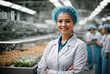 successful food factory women manager in sterile uniform with arms crossed smiling at the camera. hair net