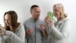 © Oleksandra - man father and husband stand with money rejoicing in life daughter and wife come and take all money man spreads his arms to the sides frustrated remains alone tracksuits. Cheerful family dollars euros