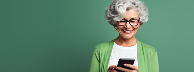 An elderly woman smiling and laughing with her phone against a colored background.