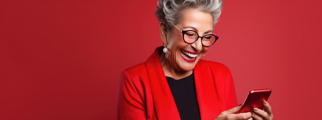 Wall Mural - An elderly woman smiling and laughing with her phone against a colored background.