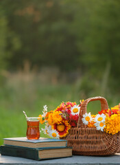 Wall Mural - turkish glass tea cup, books and flowers in basket on table in garden, abstract natural background. summer season. beautiful romantic composition. reading, relax, tea time.