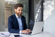 © Tetiana - Mature experienced businessman in business suit working on laptop inside office at workplace, man satisfied with achievement results smiling, typing on keyboard
