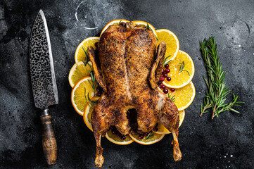 Christmas dinner, baked duck with rosemary and oranges, crispy whole roast duck. Black background. Top view