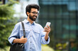 © Prostock-studio - Cheerful indian guy going to office, using cell phone