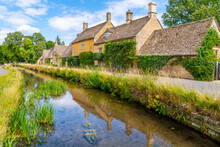 A Picturesque Row Of Stone Homes Along The River Eye In The Idyllic Country Village Of Lower Slaughter, In The Cotswold District Of Gloucestershire, England, UK.