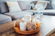 Autumn fall cozy mood composition for hygge home decor. Orange pumpkins decorated with mandalas, white blown candles with smoke on wicker tray on the coffee table in the living room. Selective focus.
