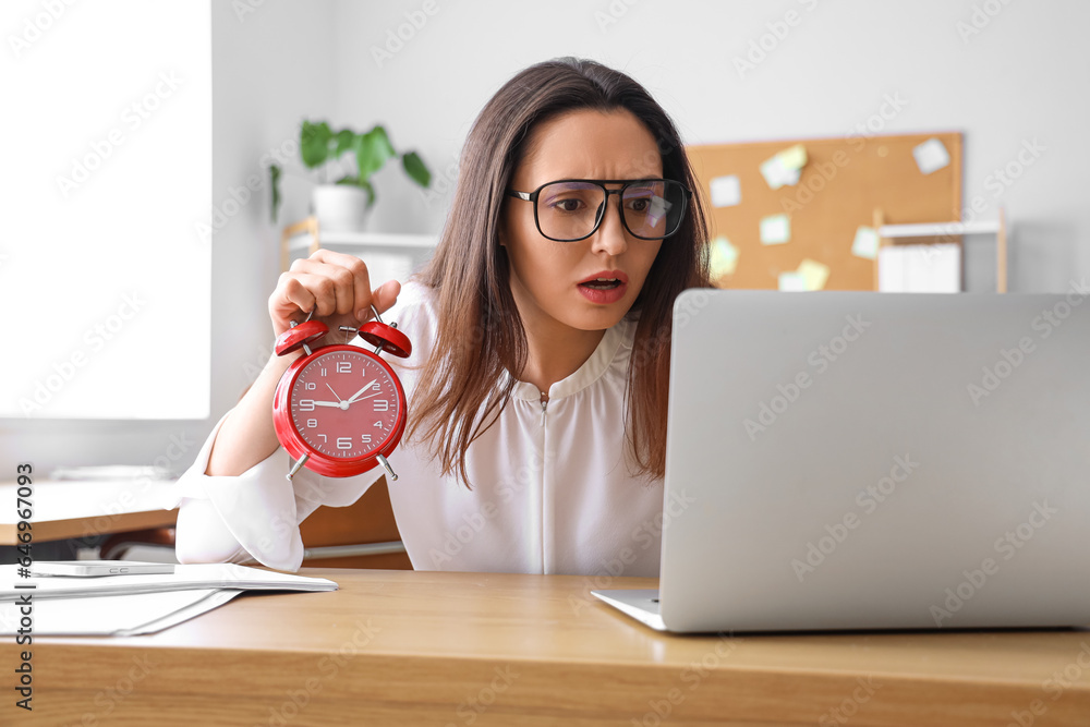 Stressed young businesswoman working under deadline in office