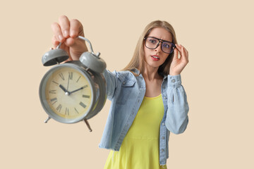 Wall Mural - Stressed young woman with alarm clock on beige background. Deadline concept