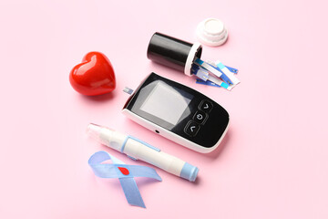 Wall Mural - Glucometer, red heart, lancet and blue ribbon on pink background. Diabetes concept