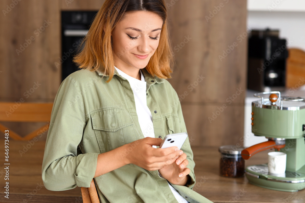 Young woman using mobile phone in kitchen