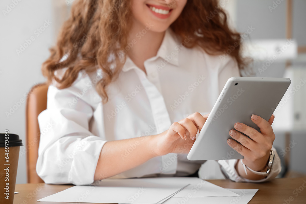 Young businesswoman working with tablet computer in office, closeup