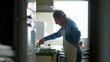 © Marco - Retired Chef in Apron Focused on Home Cooking, candid senior man preparing food by kitchen stove