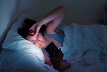 Nocturnal Struggles: A Woman's Battle Against Insomnia And Social Media Addiction Unfolds In The Soft Glow Of Her Phone