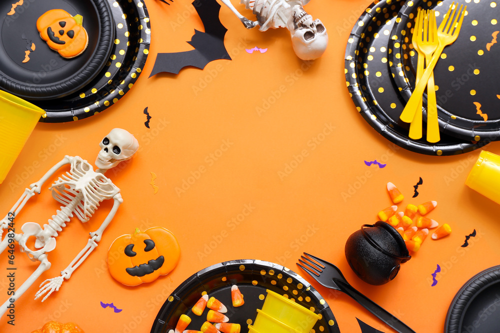 Frame made from festive table setting with Halloween decorations on orange background