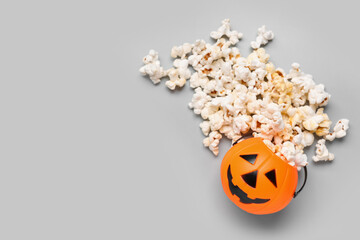 Wall Mural - Bowl made of pumpkin with tasty popcorn for Halloween celebration on grey background