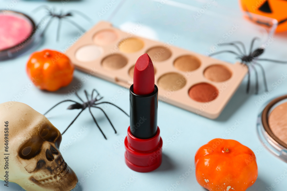 Different decorative cosmetics and Halloween decor on blue background