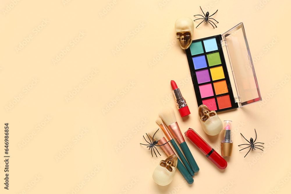 Lipsticks and different decorative cosmetics with Halloween decor on beige background