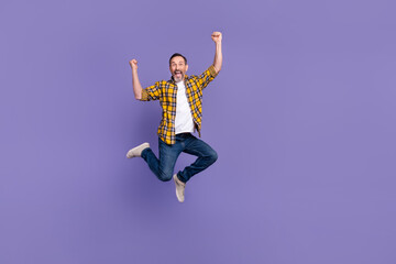 Wall Mural - Photo of cheerful astonished positive man wear stylish checkered jeans clothes hands fist empty space isolated on purple color background