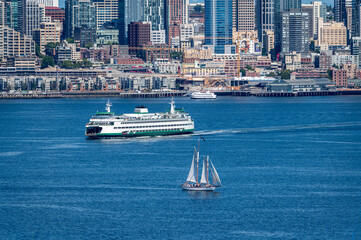 Wall Mural - Ferryboat with the Seattle skyline in the background. Ferryboat sailing to Bainbridge Island with a sailboat under way on Elliott Bay in the foreground. A lovely summer day in the Emerald City.