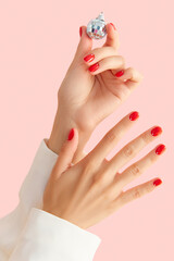 Poster - Womans hands with red manicure on pink background. Minimalist nail design