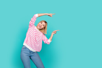 Sticker - Photo of young attractive girl pointing fingers empty space photo banner invite family clothes boutique isolated on blue color background