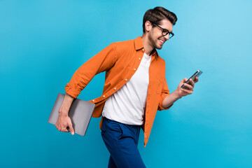 Wall Mural - Profile photo of handsome manager man walking hold netbook use smart phone texting isolated on blue color background