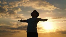 Boy Child Raised His Hands To Sky In Park At Sunset, Childhood Dreams. Happy Family. True Faith. Little Boy Prays Against Background Of Sky, Sun. Religion And God, Child Boy Plays In Park Against Sky