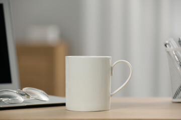 Poster - White ceramic mug, glasses and laptop on wooden table at workplace