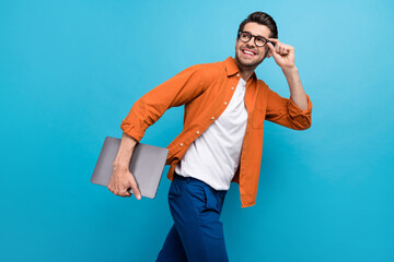 Wall Mural - Profile photo of positive corporate agent walk hold netbook hand touch eyewear look empty space isolated on blue color background