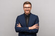 © DimaBerlin - Portrait of happy successful confident businessman in suit with crossed arms on chest smiling looking at camera on grey background. Man entrepreneur in eyeglasses on advertisement poster, banner.