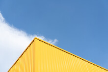 Colorful yellow metal building wall  against blue sky background.