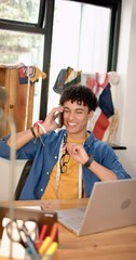 Wall Mural - Vertical video of biracial male fashion designer talking on smartphone in studio, slow motion