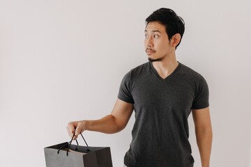 Sad disappointed and confused face of Asian man with shopping bag.